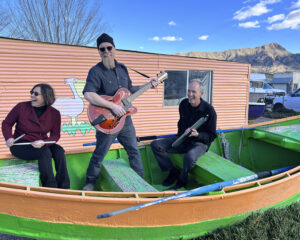 Three members of Mineral Hill Band in a boat, on dry land